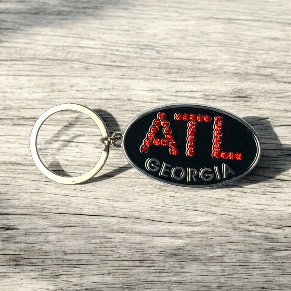 Metal keychain with 'ATL Georgia' text on a wooden surface