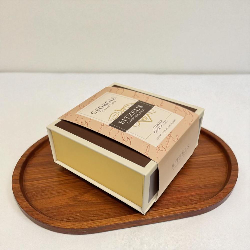 Box of artisan chocolates on a wooden tray with a white background