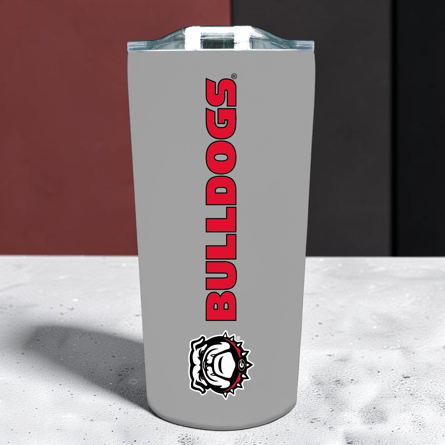 A gray insulated tumbler with a clear lid, featuring the word &