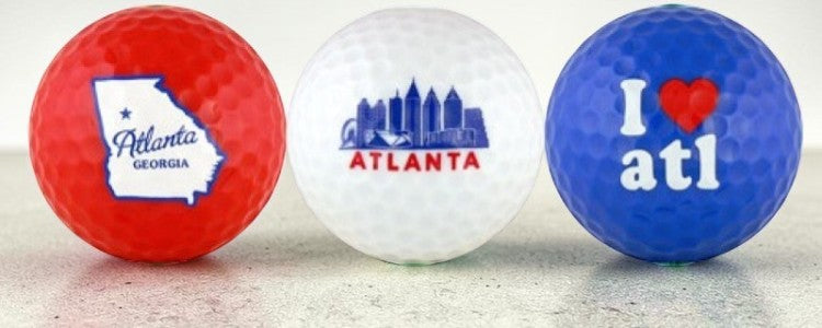 Three golf balls with Atlanta-themed designs on a light background
