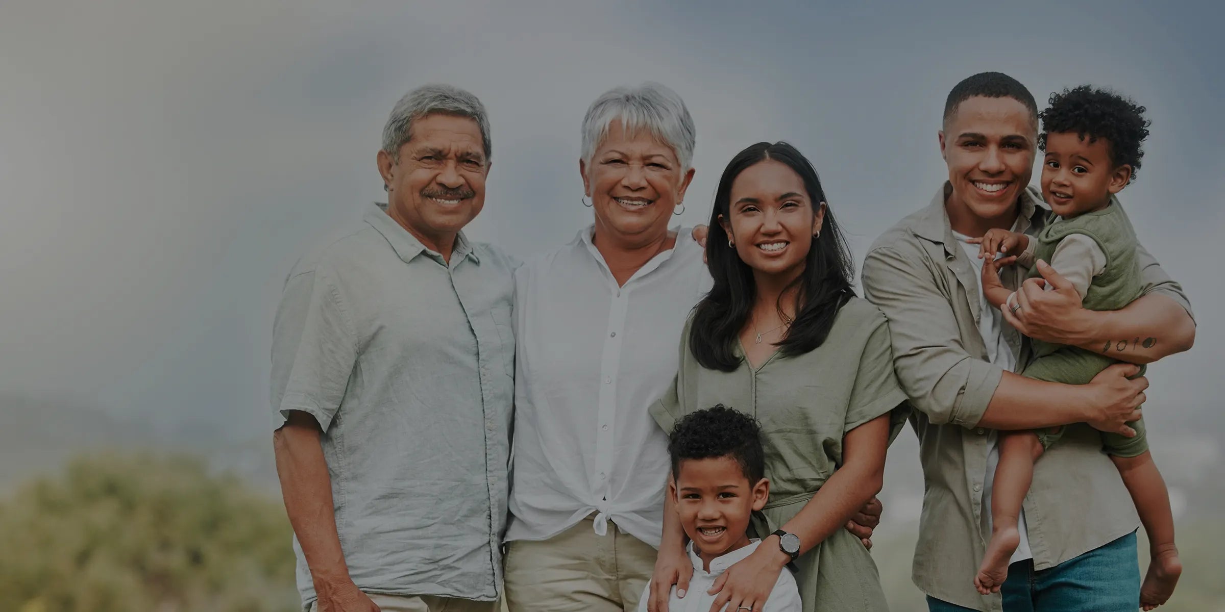 Multigenerational family posing outdoors with a blurred background