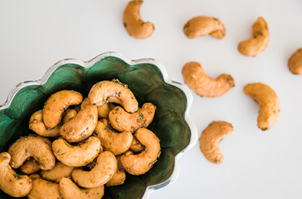 Cashew nuts in a green bowl on a white background