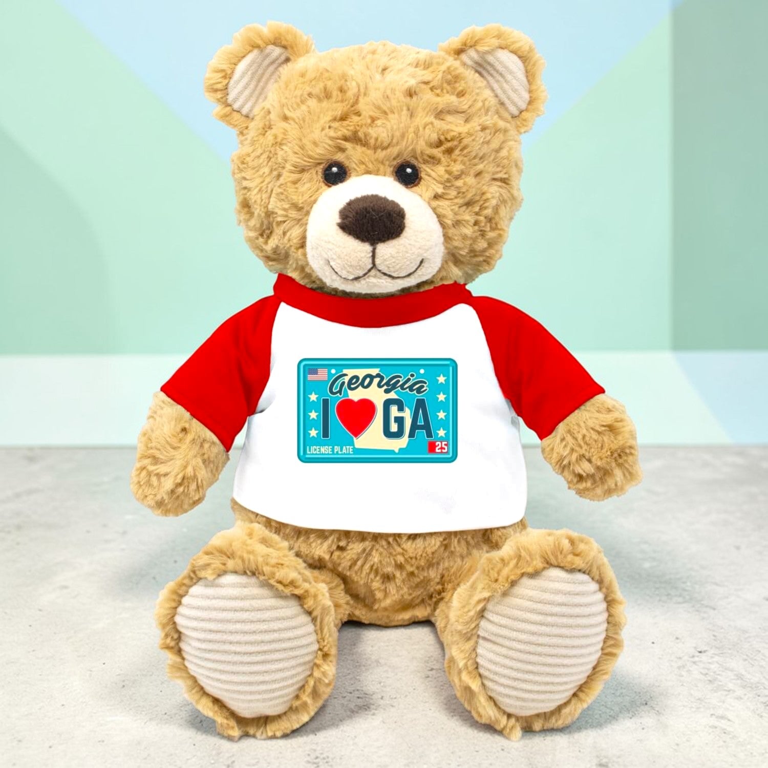 Plush teddy bear wearing a red and white shirt with a Georgia license plate design on a light background