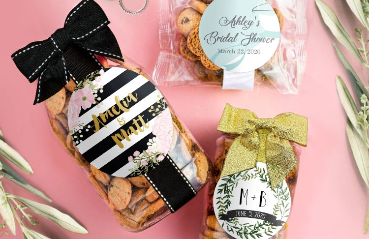 Two gift bags of bite size coolies with personalized labels on a pink background