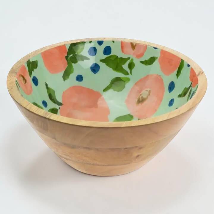 Wooden bowl with a peach patterned interior on a white background