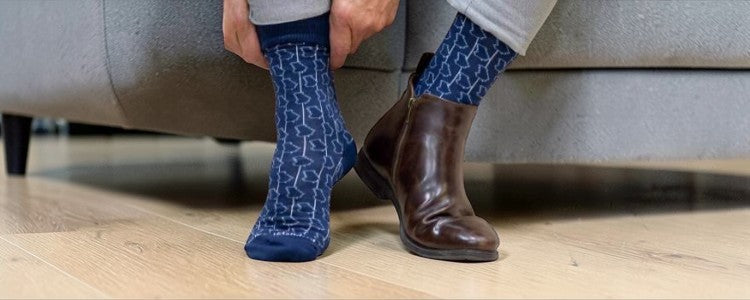 Person wearing blue Georgia patterned socks and brown boots sitting on a couch.