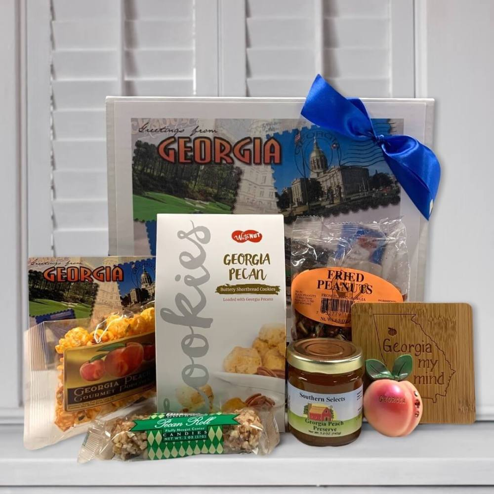 Collection of Georgia-themed gifts and various snacks including cookies, peanuts, and a jar of preserves on a white surface.