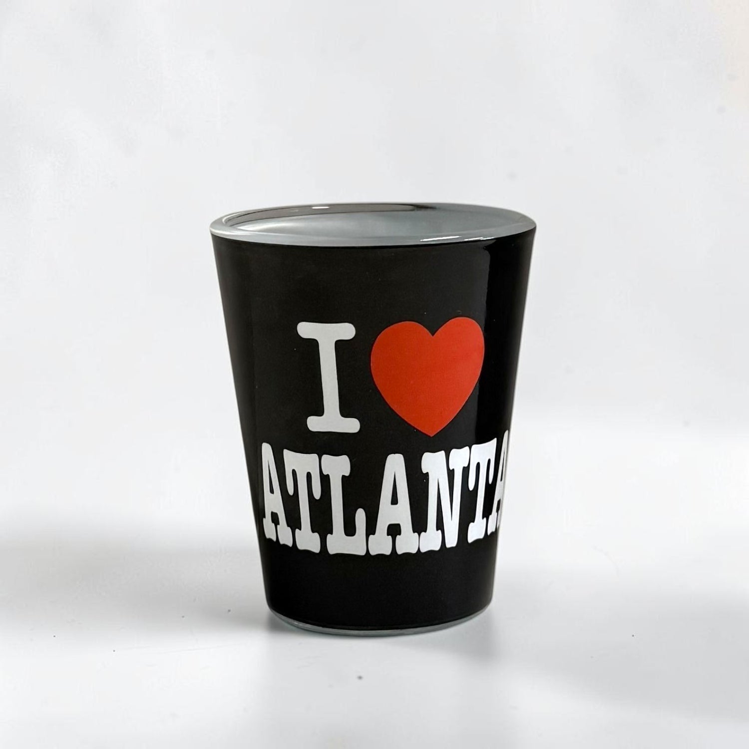 A black shot glass featuring a white &