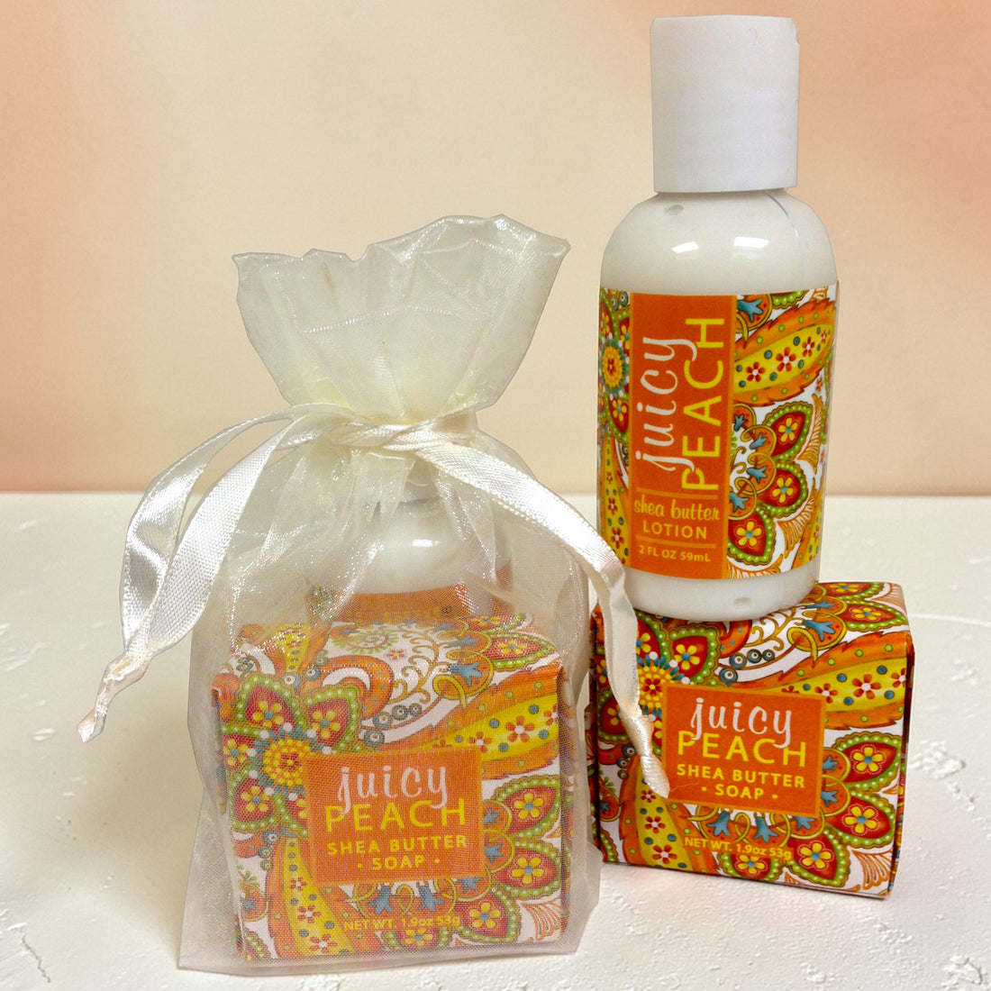 Juicy Peach shea butter products including soap, lotion, and packaging on a white surface.