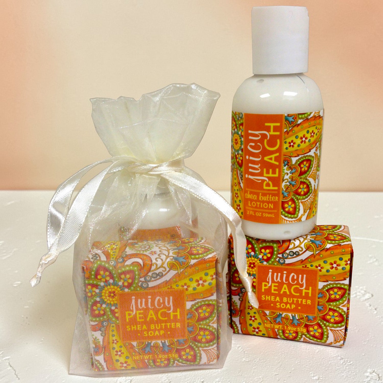 Juicy Peach shea butter products including soap, lotion, and packaging on a white surface.