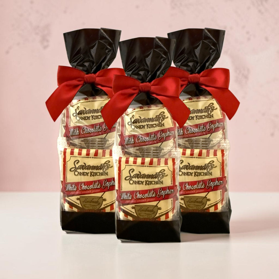 Three packaged candy gift bags tied with red satin bows, each containing Savannah&