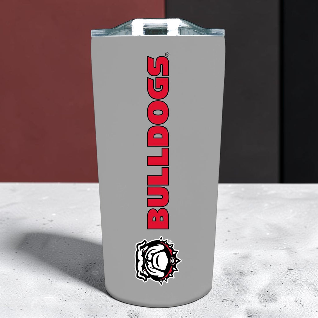 A gray insulated tumbler with a clear lid, featuring the word &