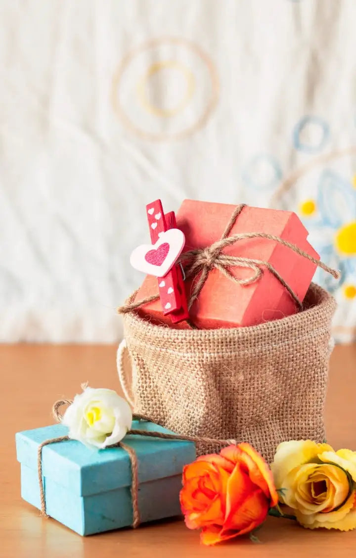 Decorative gift boxes with ribbons and flowers on a wooden surface