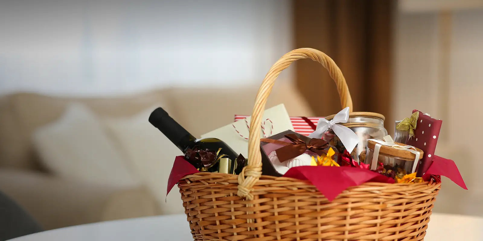 Wicker gift basket with wine and snacks on a blurred background