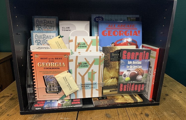 Collection of books on a wooden surface with a dark green wall background.