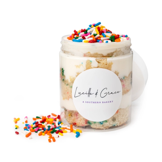 Cake jar with colorful sprinkles and a Lucille &amp; Grace label on a white background