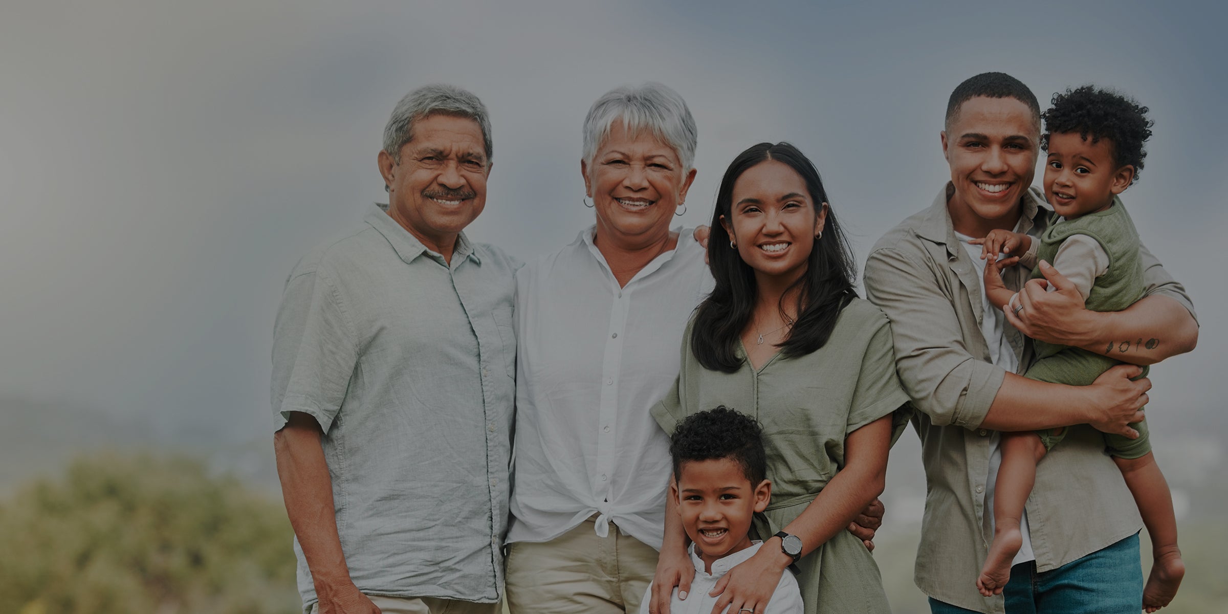 Family of six posing outdoors with a scenic background