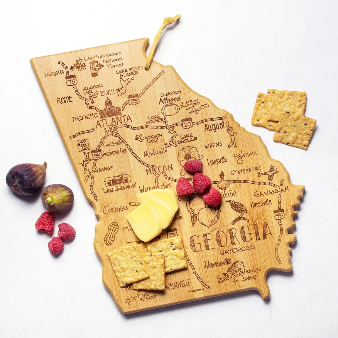 Wooden cutting board shaped like the state of Georgia with engraved details, surrounded by food items on a white background.