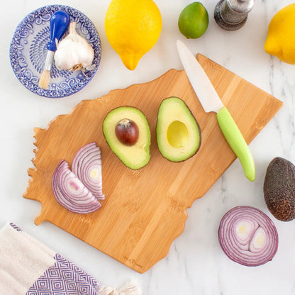 Wooden cutting board in the shape of Georgia with sliced avocado, red onion, and a knife on a marble surface.