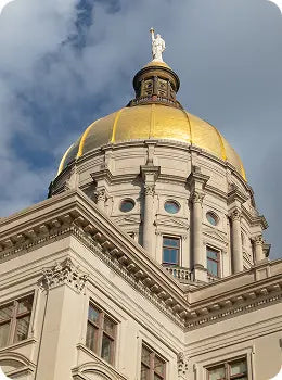 Gold-domed Georgia state capitol building with intricate architectural details against a blue sky