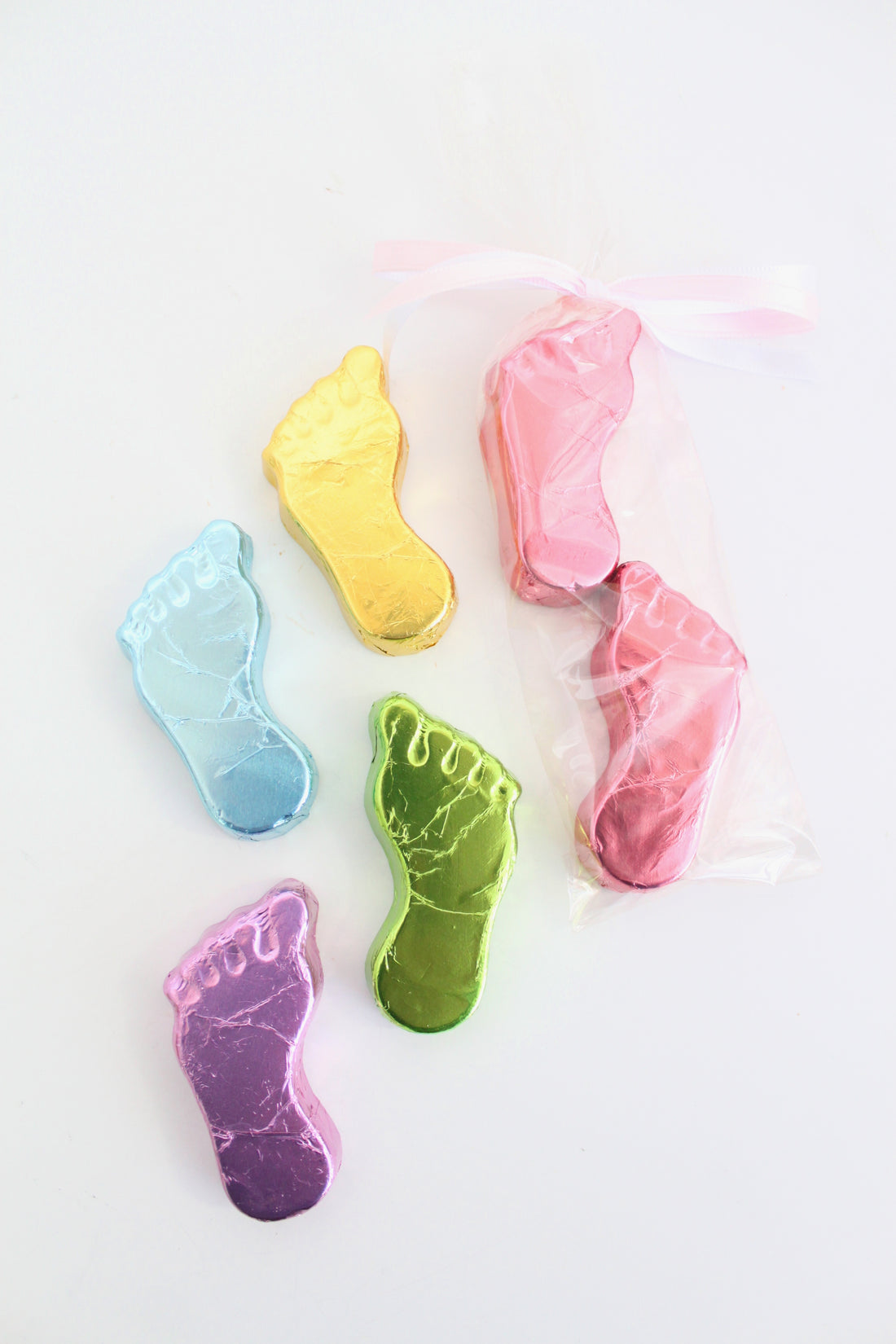Foot-shaped chocolates wrapped in color foil on a white background
