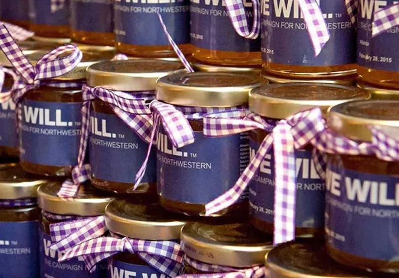 Jars of jelly with blue labels and purple checkered ribbons arranged in a stack.