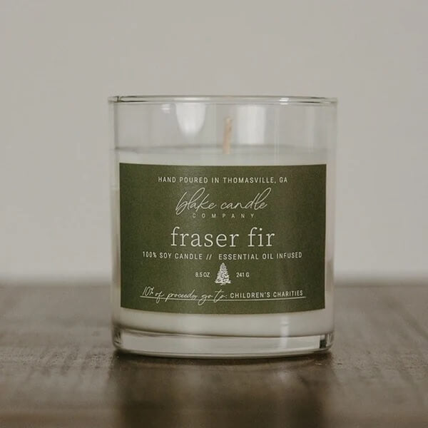 Fraser Fir Candle Jar with a green label on a wooden surface