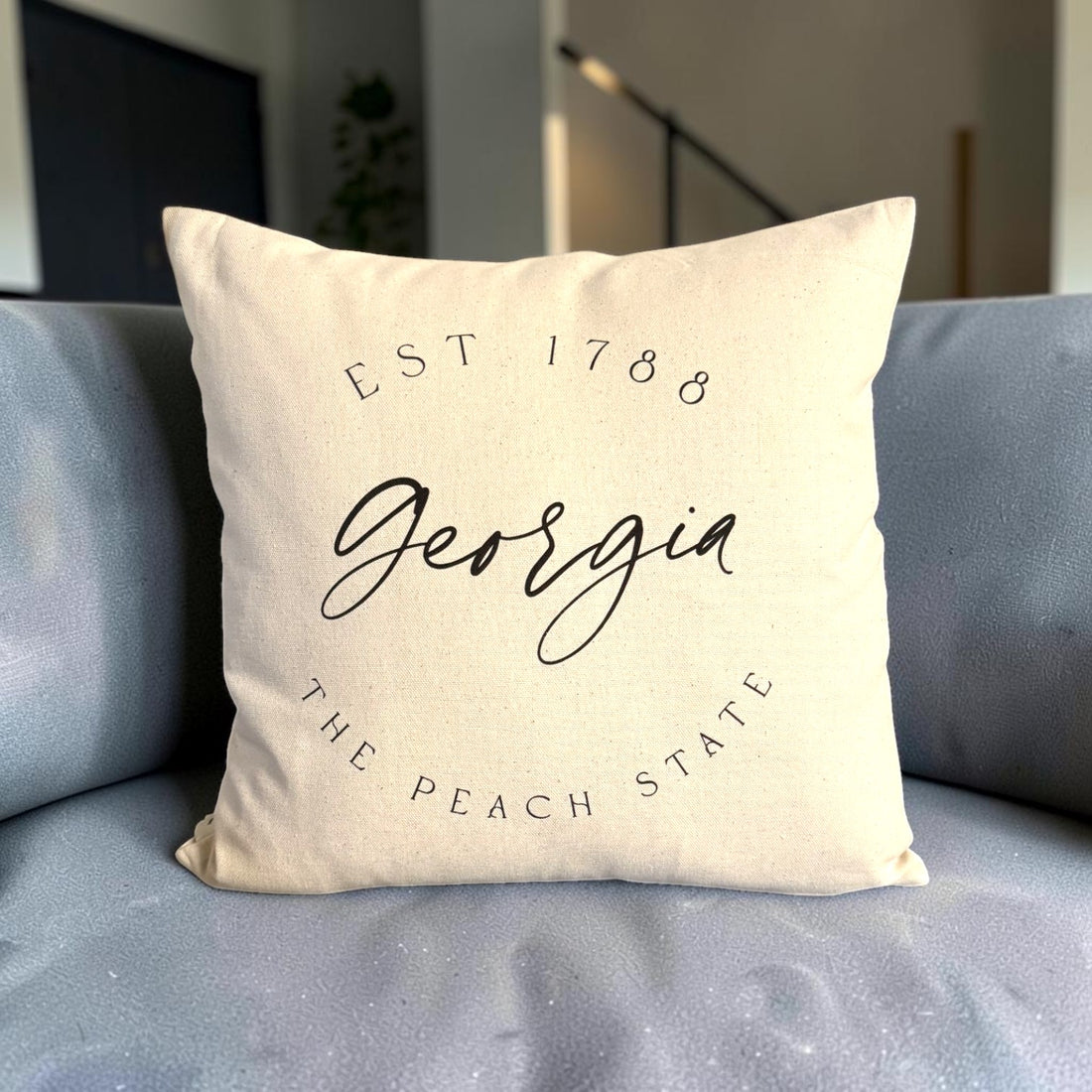 A square cream-colored throw pillow with black printed text reading &