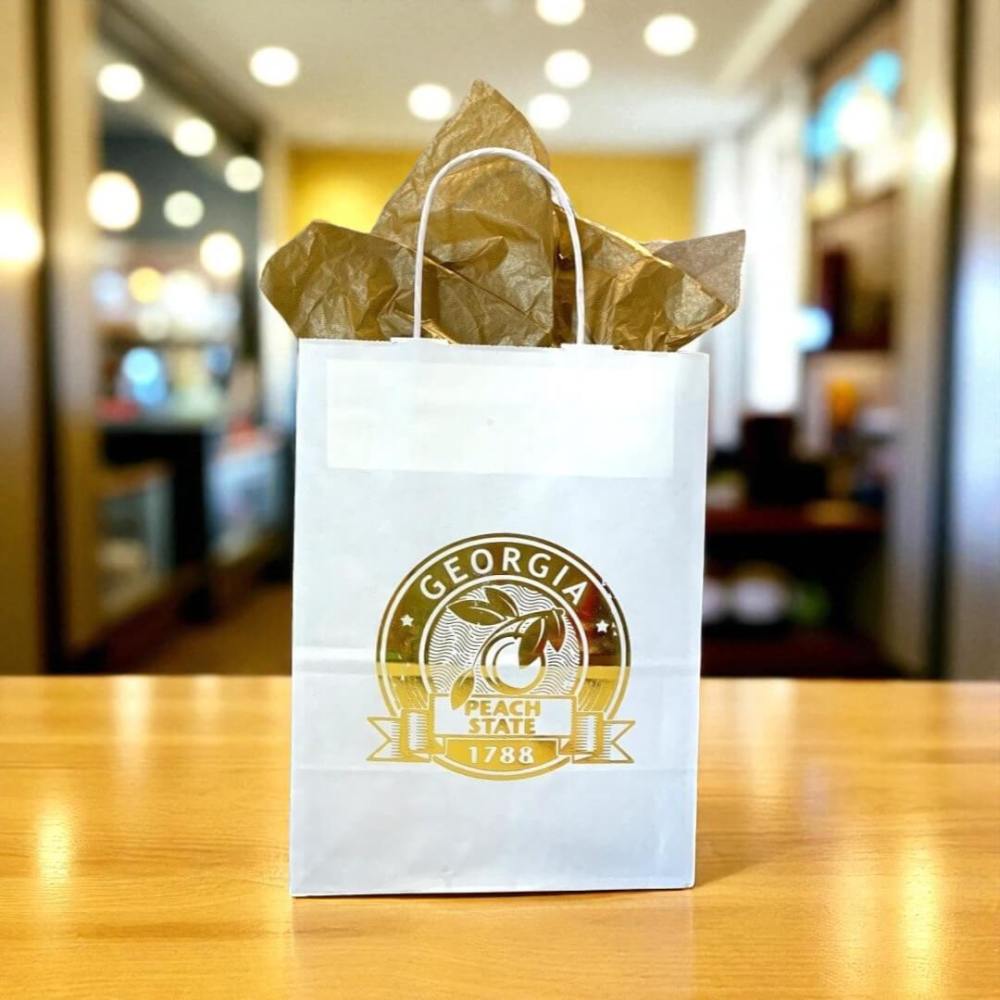 White gift bag with state of Georgia seal in metallic gold