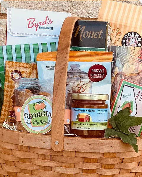 Wooden gift basket with various Georgia grown products including a jar of preserves and a box of cookies.