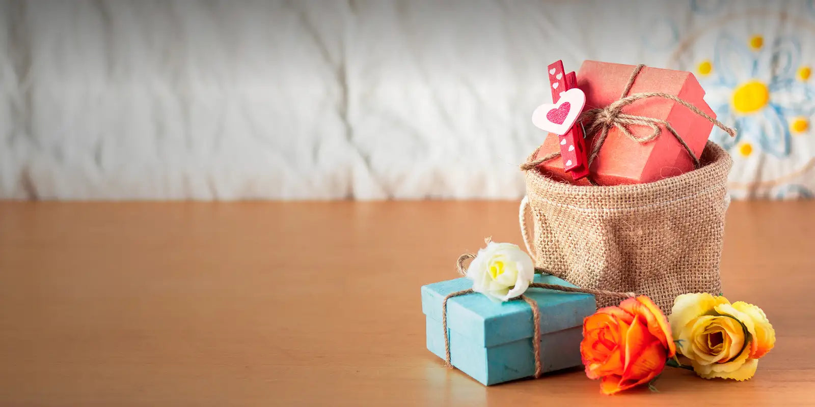 Small gift boxes and flowers on a wooden surface with a blurred background