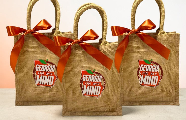 Three burlap bags with rust color ribbons and 'Georgia on my Mind' logo on a light background