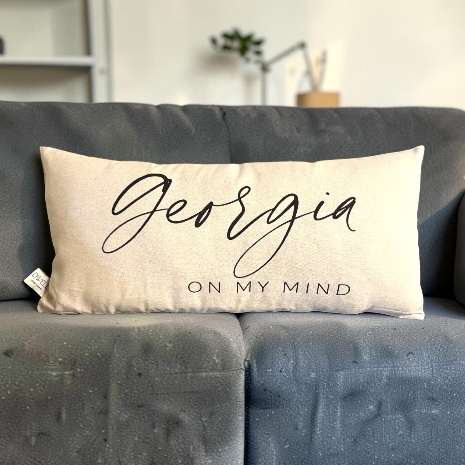 A rectangular cream throw pillow with black script reading &
