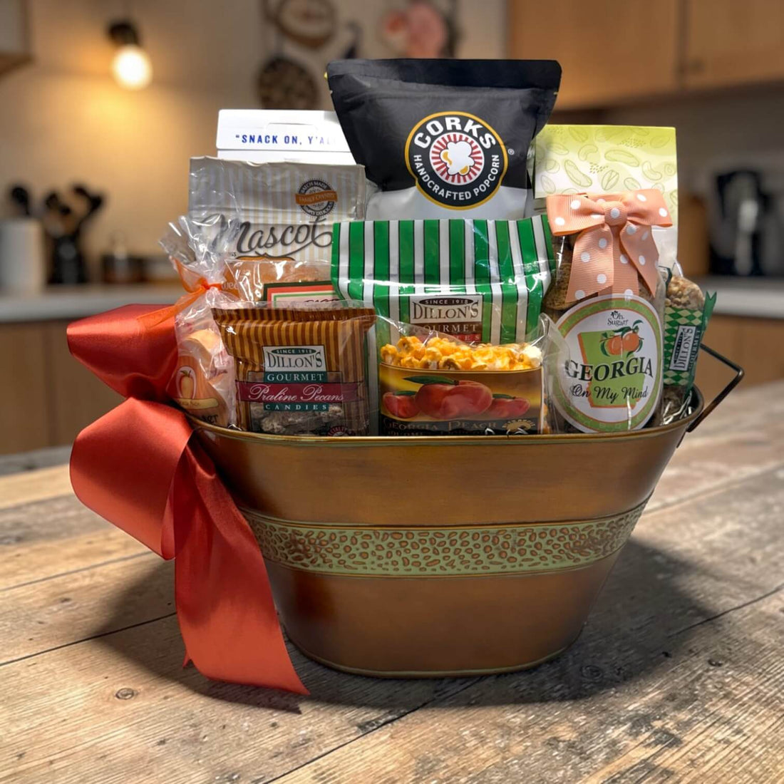 Gift basket with Georgia grown snacks in a copper metal tin sitting on a wooden table in a kitchen setting