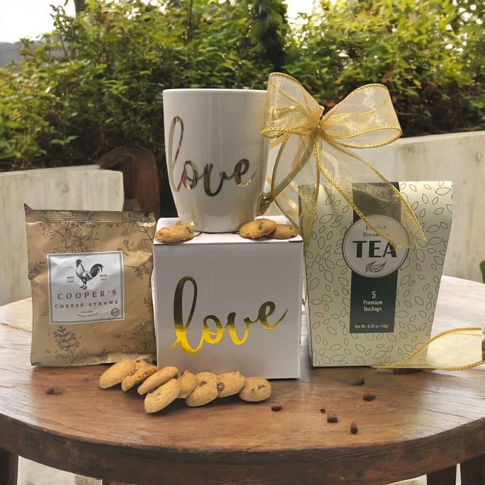 Ceramic Love mug with gold accents along with cookies, cheese straws and tea gift set