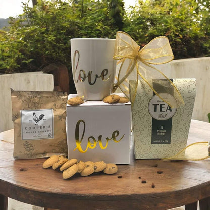 Ceramic Love mug with gold accents along with cookies, cheese straws and tea gift set
