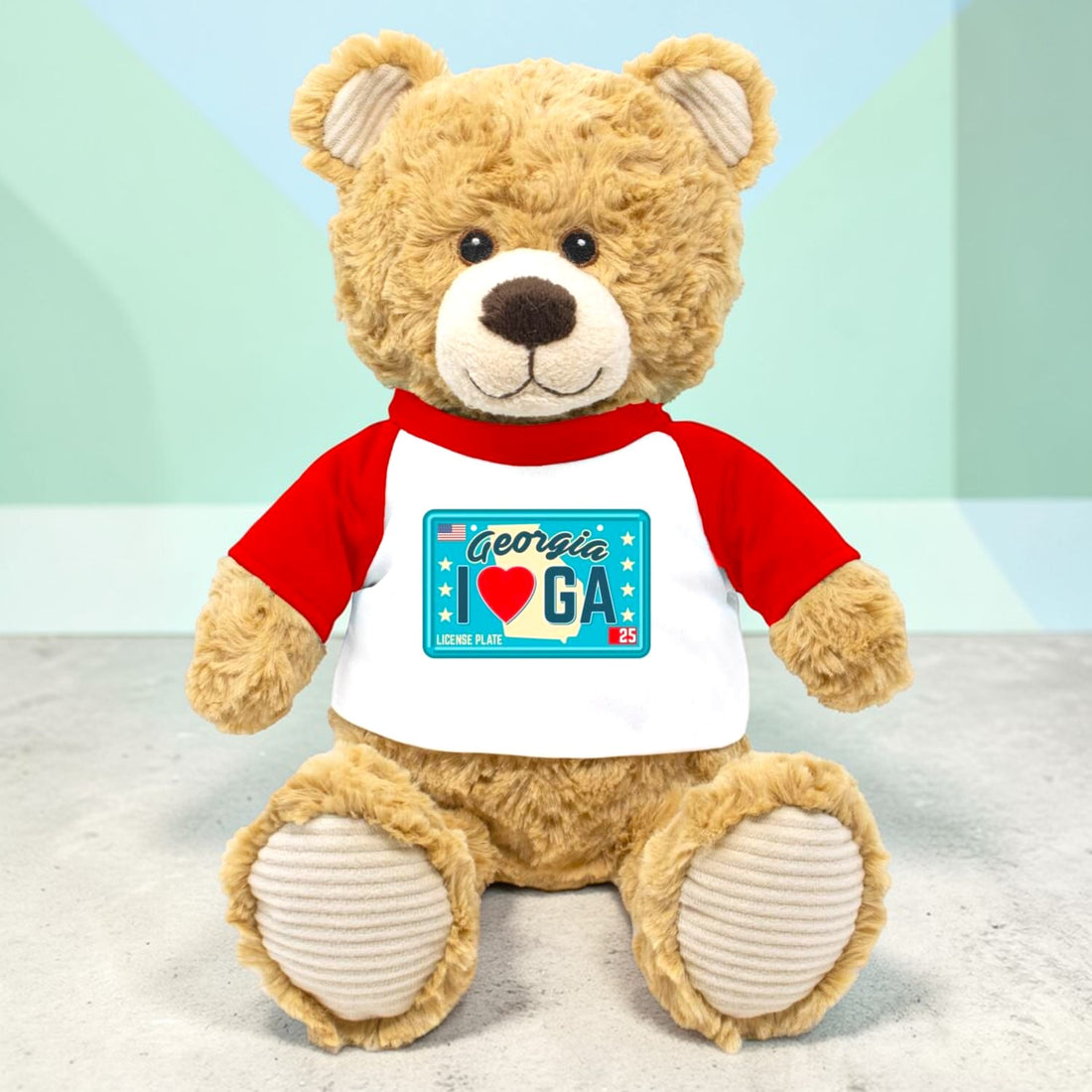 Plush teddy bear wearing a red and white shirt with a Georgia license plate design on a light background