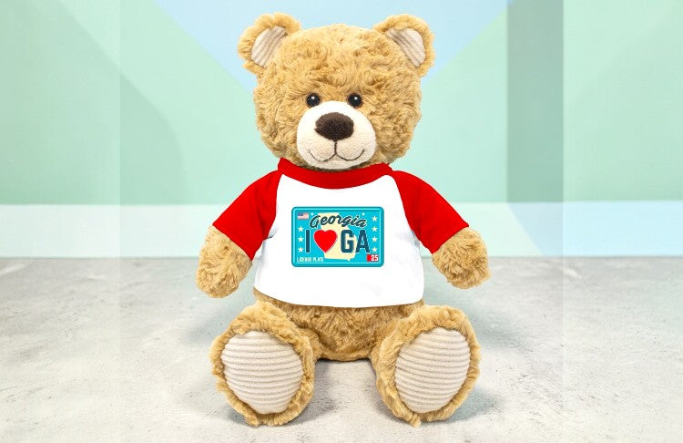 Teddy bear wearing a red and white shirt with a Georgia license plate design on a light background