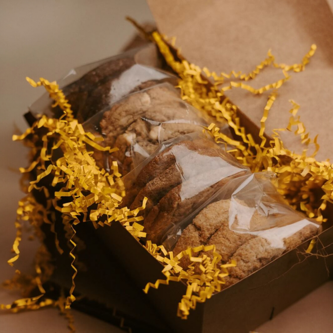 Packaged fresh baked cookies with gold crinkle paper in a box