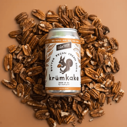 Can of butter pecan cream soda laying on a bed of unshelled pecans.