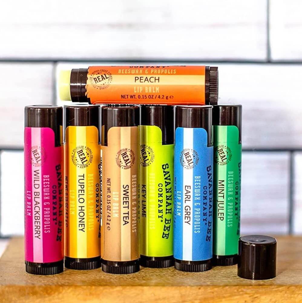 Seven flavors of lip balm from Savannah Bee displayed on wooden shelf