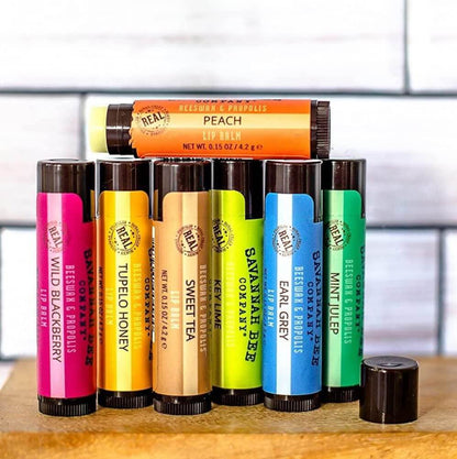 Seven flavors of lip balm from Savannah Bee displayed on wooden shelf