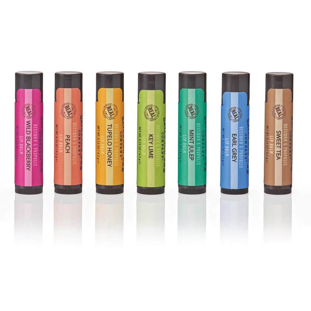 Set of seven Savannah Bee lip balms with colorful packaging on a white background