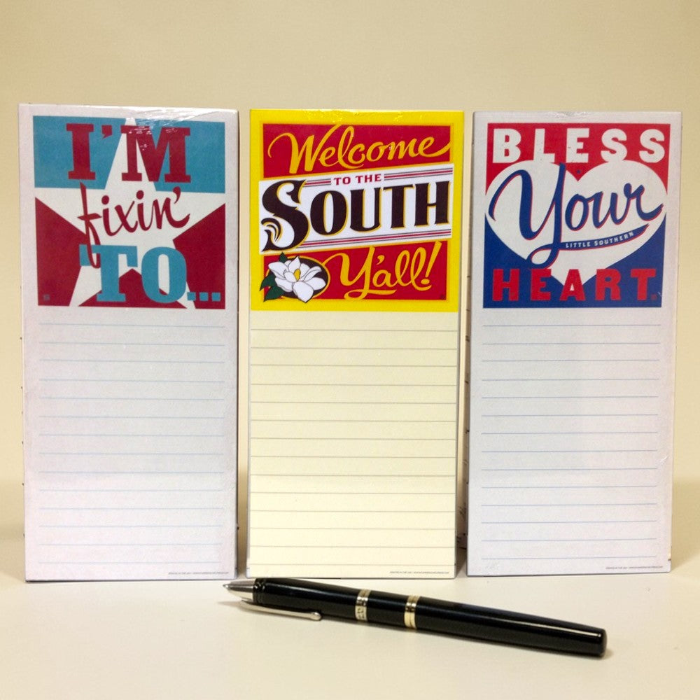 Three notepads with humorous Southern sayings and a pen on a beige background