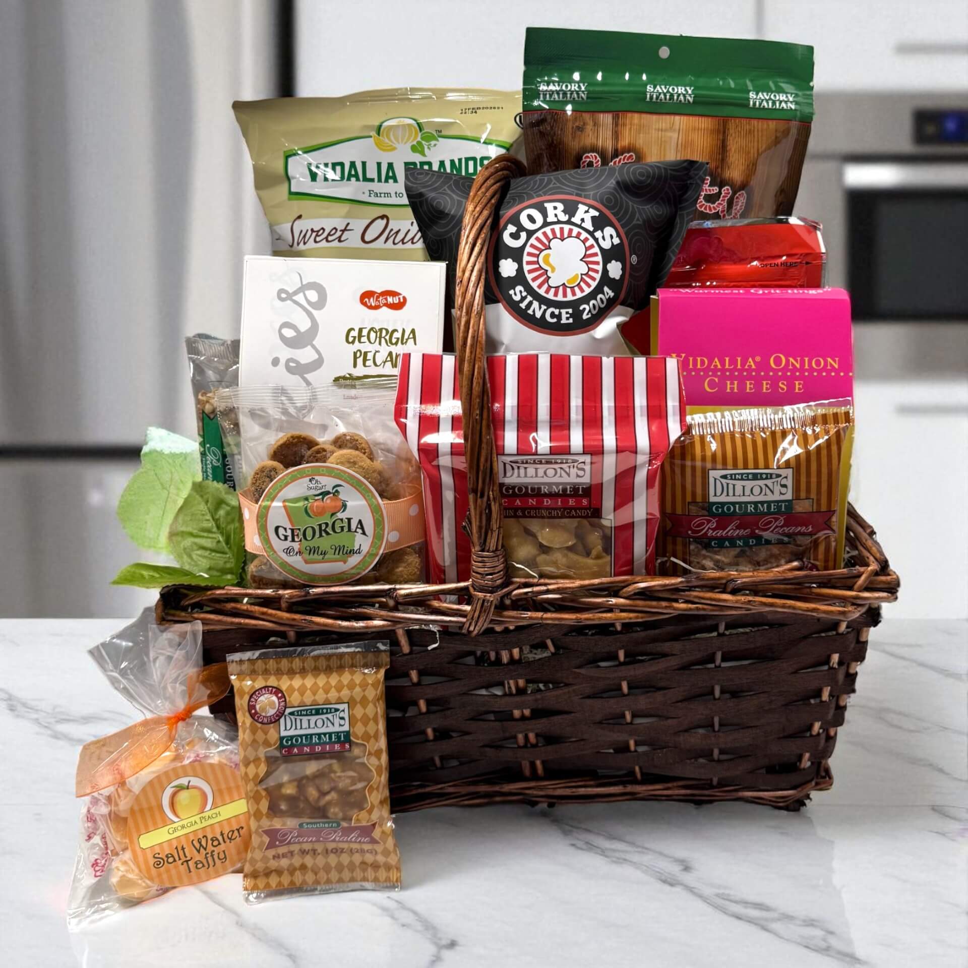 Gourmet gift basket with various Georgia Grown snacks and treats in a wicker basket on a kitchen counter.
