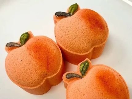Three peach-shaped bath bombs on a white plate
