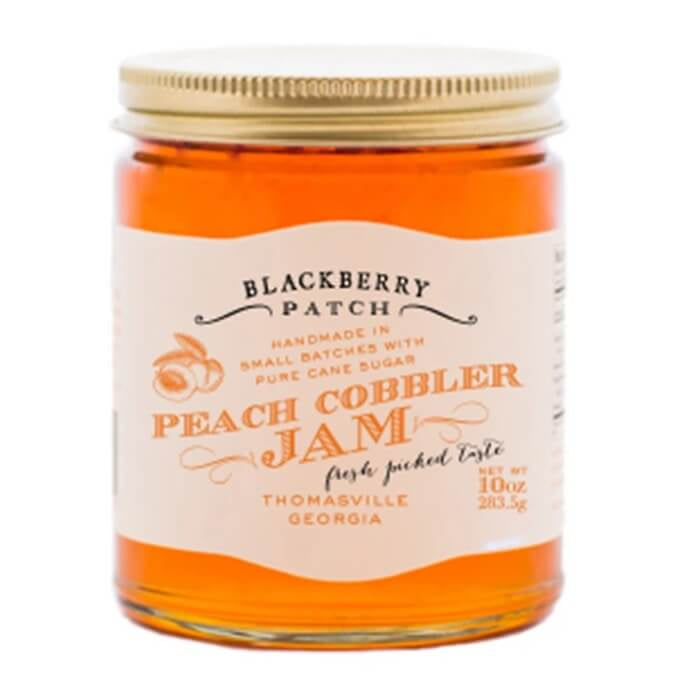 Jar of Blackberry Patch Peach Cobbler Jam with a gold lid on a white background