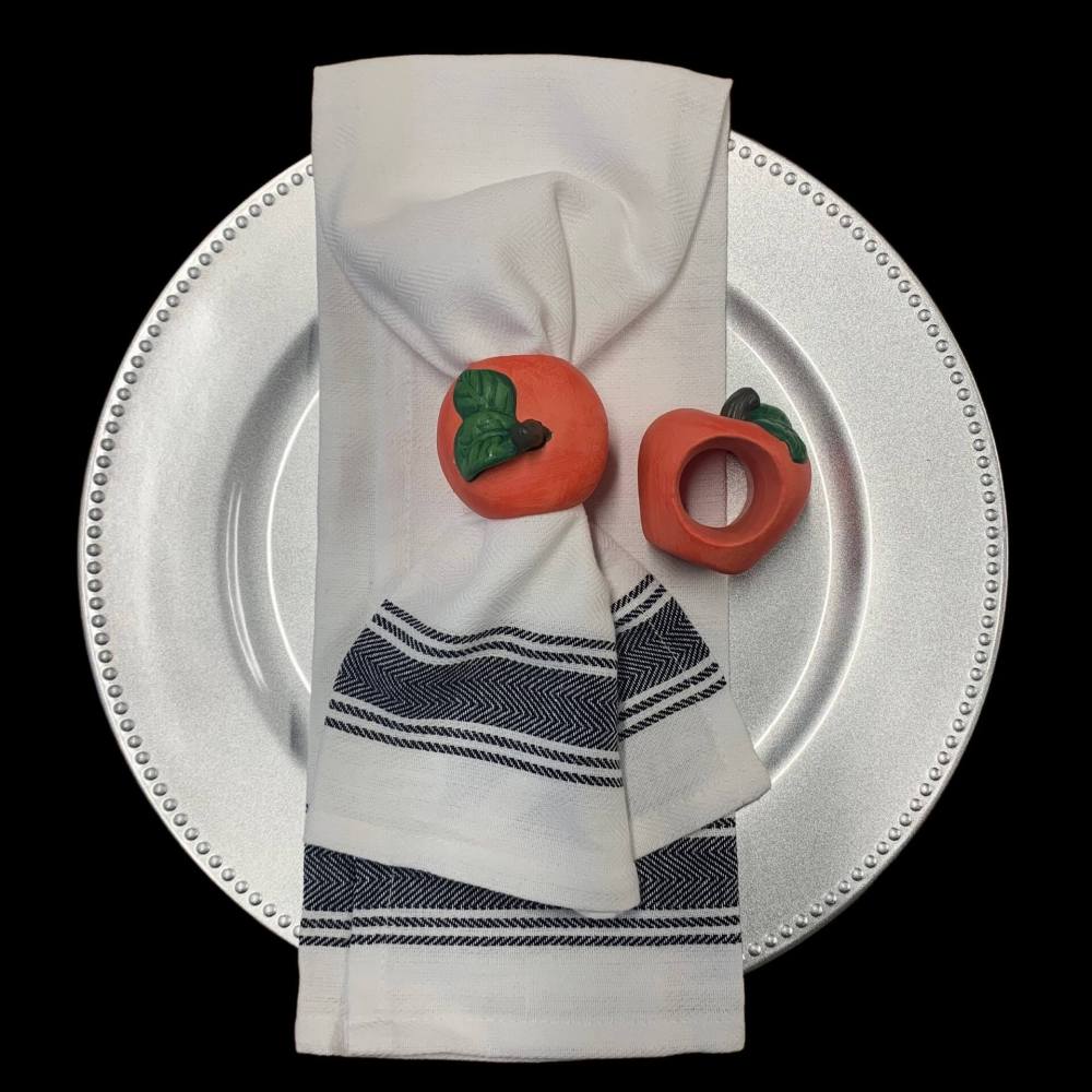 Ceramic napkin ring in the shape of a peach shown around a napkin and by itself.