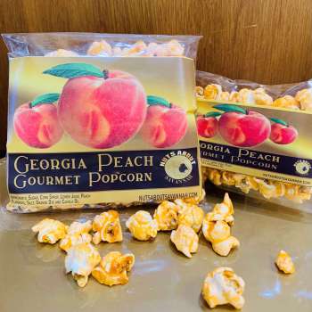 Georgia Peach Gourmet Popcorn packaging in two sizes with popcorn on a metallic surface