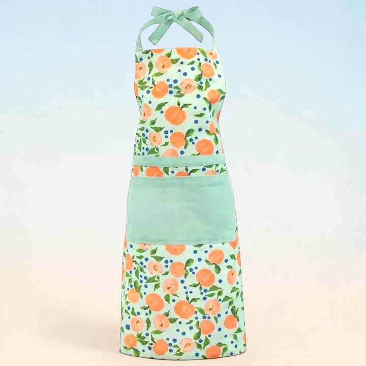 Light green apron with watercolor peach pattern and a green bow on a light blue and beige gradient